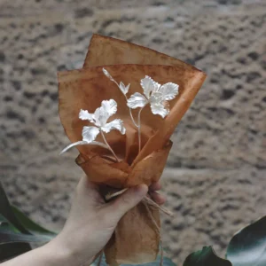 Hand holding a delicate Iris Bouquet wrapped in parchment paper, symbolizing Lazesoul Handmade Art Gifts. Features 925 sterling silver design, perfect as timeless Art Gifts with nature-inspired elegance.