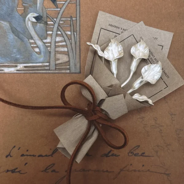 Handmade 925 sterling silver mini Calla Lily Bouquet wrapped in rustic brown paper with suede cord, styled with vintage swan art background. Unique Lazesoul Art Gifts for nature lovers, perfect for timeless, elegant gifting.
