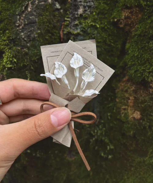 Hand holding a handmade Calla Lily Bouquet with delicate white flowers, crafted with 925 sterling silver accents, brown paper wrap, and rustic bow — Lazesoul Handmade Art Gifts, nature-inspired elegance.
