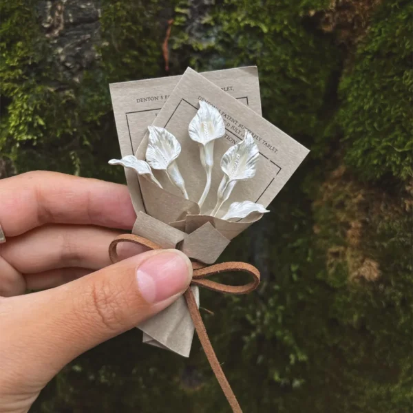 Hand holding a handmade Calla Lily Bouquet with delicate white flowers, crafted with 925 sterling silver accents, brown paper wrap, and rustic bow — Lazesoul Handmade Art Gifts, nature-inspired elegance.