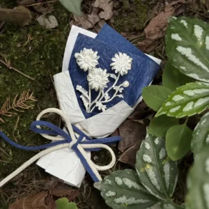 Handmade 925 sterling silver mini daisy bouquet displayed in a natural woodland setting, wrapped in textured white paper with a blue floral card. Unique Lazesoul art gifts blending nature-inspired beauty with timeless craftsmanship.