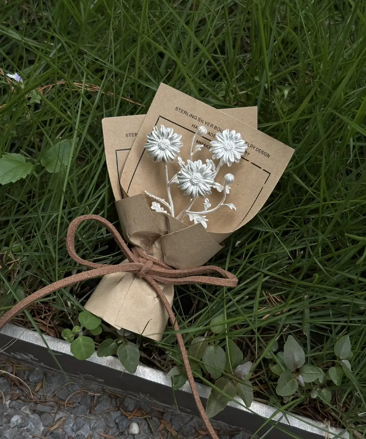 Elegant 925 sterling silver mini daisy bouquet displayed with rustic brown wrapping on green grass, perfect handmade art gift from Lazesoul. Nature-inspired jewelry for Daisy Bouquet lovers and Art Gifts collectors.