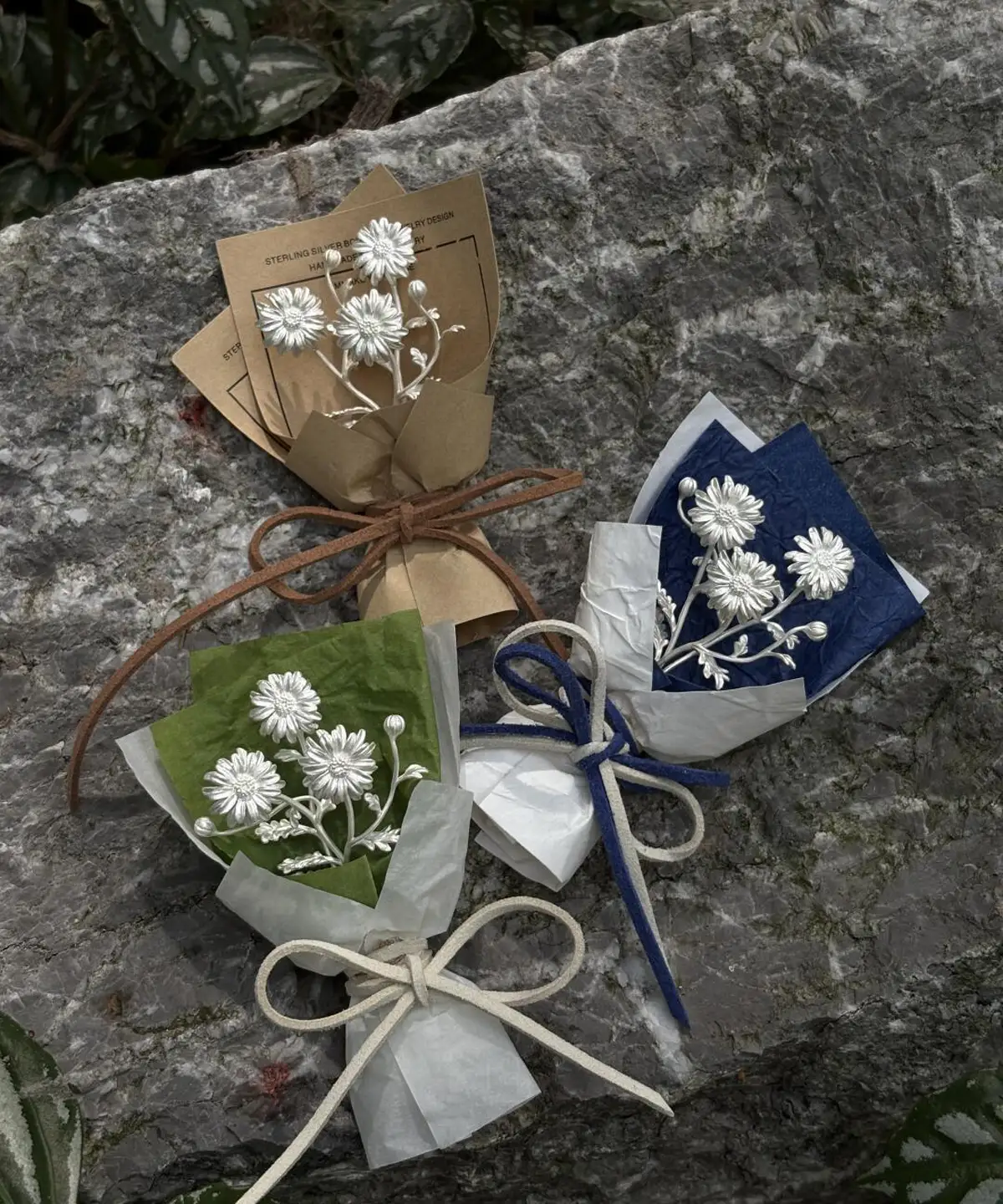 Handcrafted mini daisy bouquet with white daisies and baby’s breath, wrapped in green, brown, and blue paper. Perfect as handmade art gifts, this 925 sterling silver inspired daisy bouquet adds charm to home décor or special occasions.