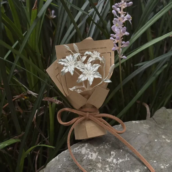 925 Sterling Silver Mini Lily Bouquet-Handmade Art Gifts 07 925 Sterling Silver Mini Lily Bouquet wrapped in rustic brown paper with suede bow, handmade by Lazesoul. Artistic blend of metallic lilies and nature, perfect for unique Lily Bouquet lovers and elegant Art Gifts.