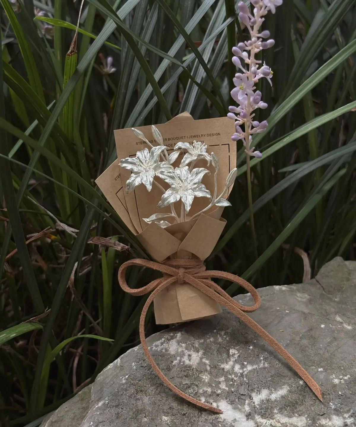 925 Sterling Silver Mini Lily Bouquet wrapped in rustic brown paper with suede bow, handmade by Lazesoul. Artistic blend of metallic lilies and nature, perfect for unique Lily Bouquet lovers and elegant Art Gifts.