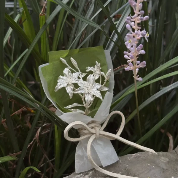 925 Sterling Silver Mini Lily Bouquet-Handmade Art Gifts 08 925 Sterling Silver Mini Lily Bouquet resting on a rock beside lavender blooms, wrapped in green and white paper with ribbon — Lazesoul Handmade Art Gifts, perfect for elegant keepsakes and nature‑inspired décor.