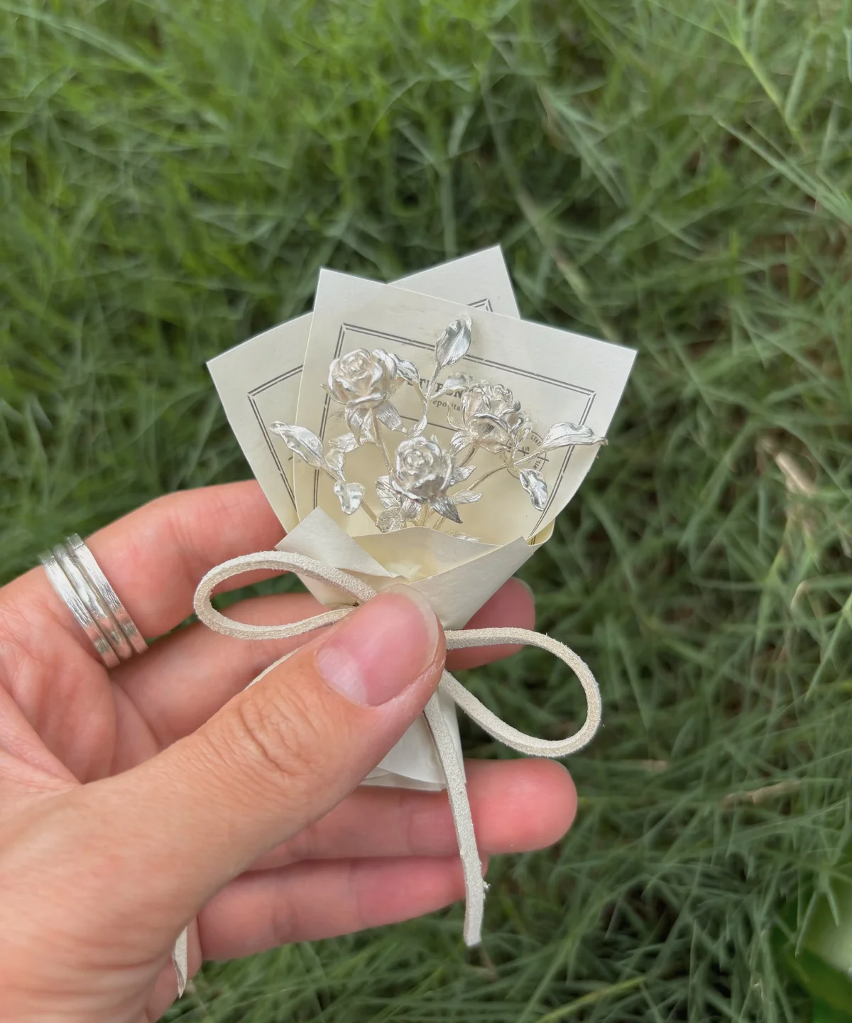 Handcrafted 925 sterling silver mini rose bouquet with delicate metal roses and leaves, tied with a white bow on a cream card. Perfect as unique handmade art gifts, ideal for collectors and lovers of elegant rose bouquet designs.
