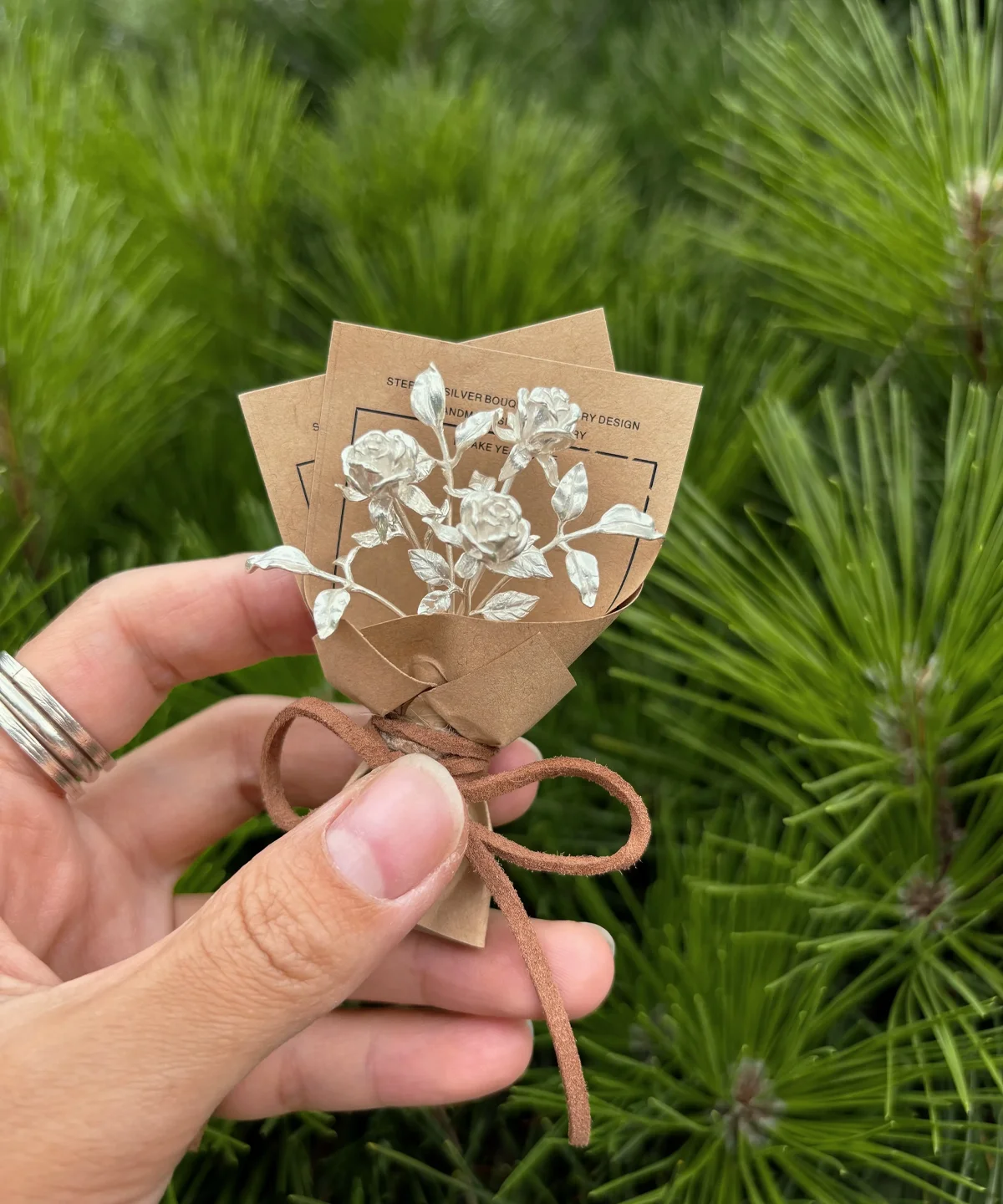 A delicate 925 sterling silver mini rose bouquet, handmade with artistic detail, wrapped in rustic brown paper with a bow. Perfect as unique art gifts, blending timeless elegance with nature-inspired charm from Lazesoul.