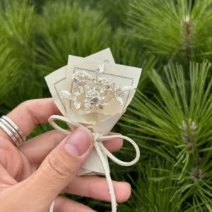 Hand holding a 925 sterling silver mini rose bouquet wrapped in paper with string bow, Lazesoul handmade art gifts, nature-inspired design, perfect rose bouquet keepsake for unique art gifts lovers.