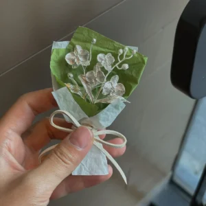 A delicate 925 sterling silver Phalaenopsis mini bouquet, handmade with intricate metallic flowers and leaves, wrapped in white and green paper with a ribbon. Perfect for Lazesoul art gifts, blending elegance and craftsmanship.