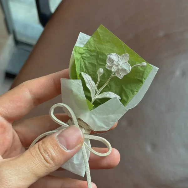 925 Sterling Silver Phalaenopsis Mini Bouquet-Handmade Art Gift 05 Elegant 925 sterling silver Phalaenopsis mini bouquet wrapped in white and green paper with a beige bow, handmade by Lazesoul. Perfect for unique art gifts, combining fine craftsmanship and timeless floral beauty.