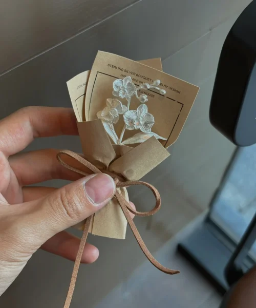 A delicate 925 sterling silver Phalaenopsis Mini Bouquet presented in brown paper with ribbon, blending floral artistry and fine jewelry. Perfect for Lazesoul Handmade Art Gifts, ideal for unique keepsakes and elegant gift-giving.