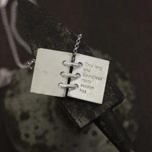 Close-up of Lazesoul Love Letter 925 sterling silver personalized book necklace, handmade with open notebook pendant engraved “This long and boundless rainy season has…,” on silver chain. Elegant custom jewelry gift.