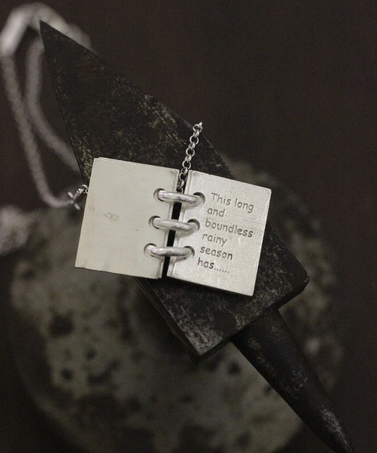Close-up of Lazesoul Love Letter 925 sterling silver personalized book necklace, handmade with open notebook pendant engraved “This long and boundless rainy season has…,” on silver chain. Elegant custom jewelry gift.