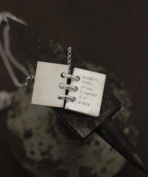 Close-up of Lazesoul Love Letter 925 sterling silver personalized book necklace, handmade with open notebook pendant engraved “suddenly think of you, I wonder if it is love,” on silver chain. Elegant custom jewelry gift.