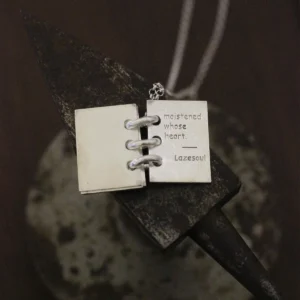 Close-up of Lazesoul Love Letter 925 sterling silver personalized book necklace, handmade with open notebook pendant engraved “moistened whose heart. Lazesoul,” on silver chain. Elegant custom jewelry gift for her.