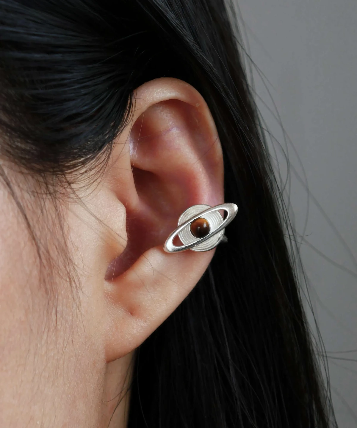 Close-up of ear wearing Lazesoul handmade Saturn Earrings in 925 sterling silver, featuring a polished tiger’s eye gemstone as Saturn with orbit-inspired bands; celestial artisan earrings blending cosmic elegance, astronomy symbolism, and timeless craftsmanship.