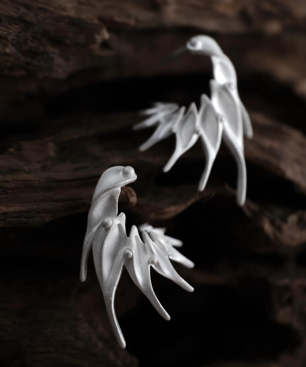Ethereal Wings S925 Sterling Silver Designer Earrings by Lazesoul. Handmade art jewelry with wing‑like curves and sculptural organic forms. Unique designer earrings crafted with elegance, artistry, and timeless sophistication against dark wood background.