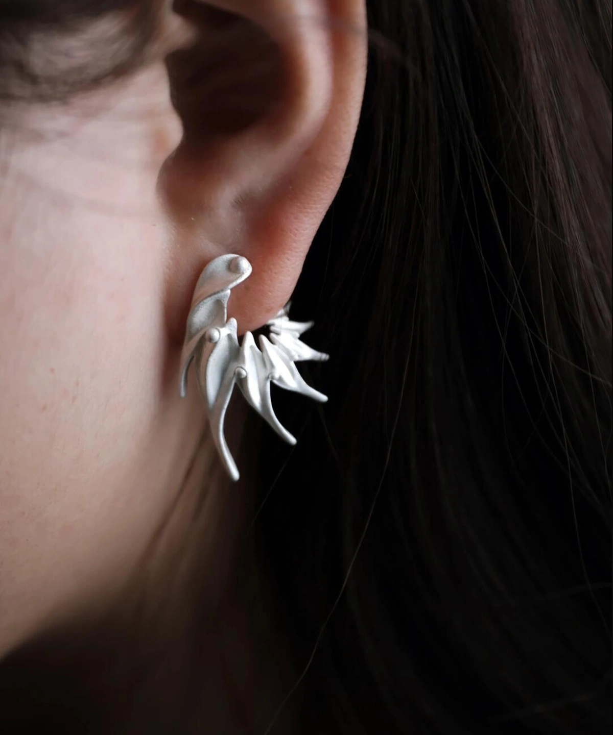 Close‑up of Lazesoul Ethereal Wings S925 Sterling Silver Designer Earrings worn on ear. Handmade art jewelry with flowing, flame‑like curves and sculptural organic design. Unique designer earrings showcasing elegance, craftsmanship, and modern sophistication.