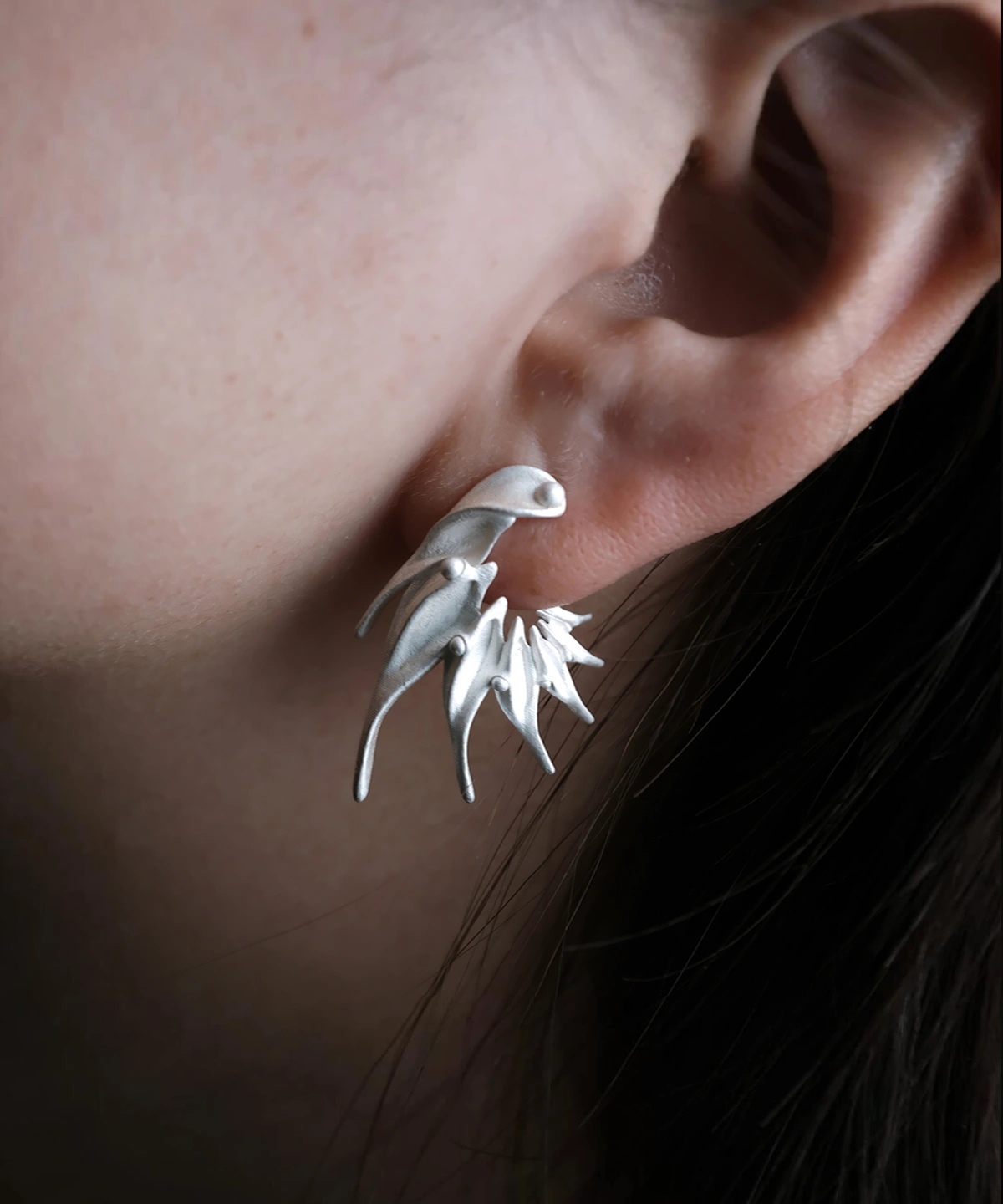Close‑up of Lazesoul Ethereal Wings S925 Sterling Silver Designer Earrings worn on ear. Handmade art jewelry with flame‑like sculptural curves and elongated silver spikes. Unique designer earrings showcasing bold, modern elegance and craftsmanship.