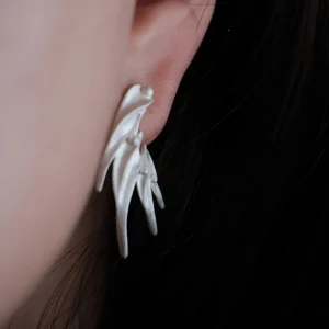 Close‑up of Lazesoul Ethereal Wings S925 Sterling Silver Designer Earrings worn on ear. Handmade art jewelry with flowing, leaf‑like curves, sculptural organic forms, and polished accents. Unique designer earrings showcasing elegance and craftsmanship.