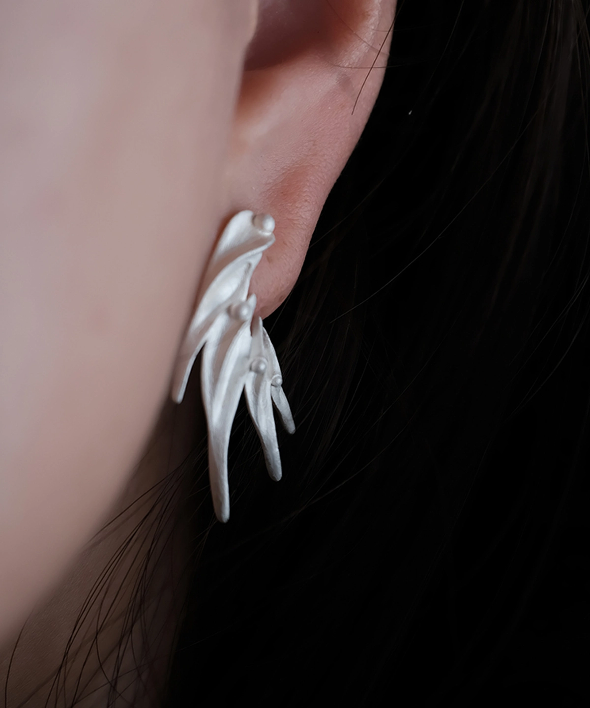 Close‑up of Lazesoul Ethereal Wings S925 Sterling Silver Designer Earrings worn on ear. Handmade art jewelry with flowing, leaf‑like curves, sculptural organic forms, and polished accents. Unique designer earrings showcasing elegance and craftsmanship.