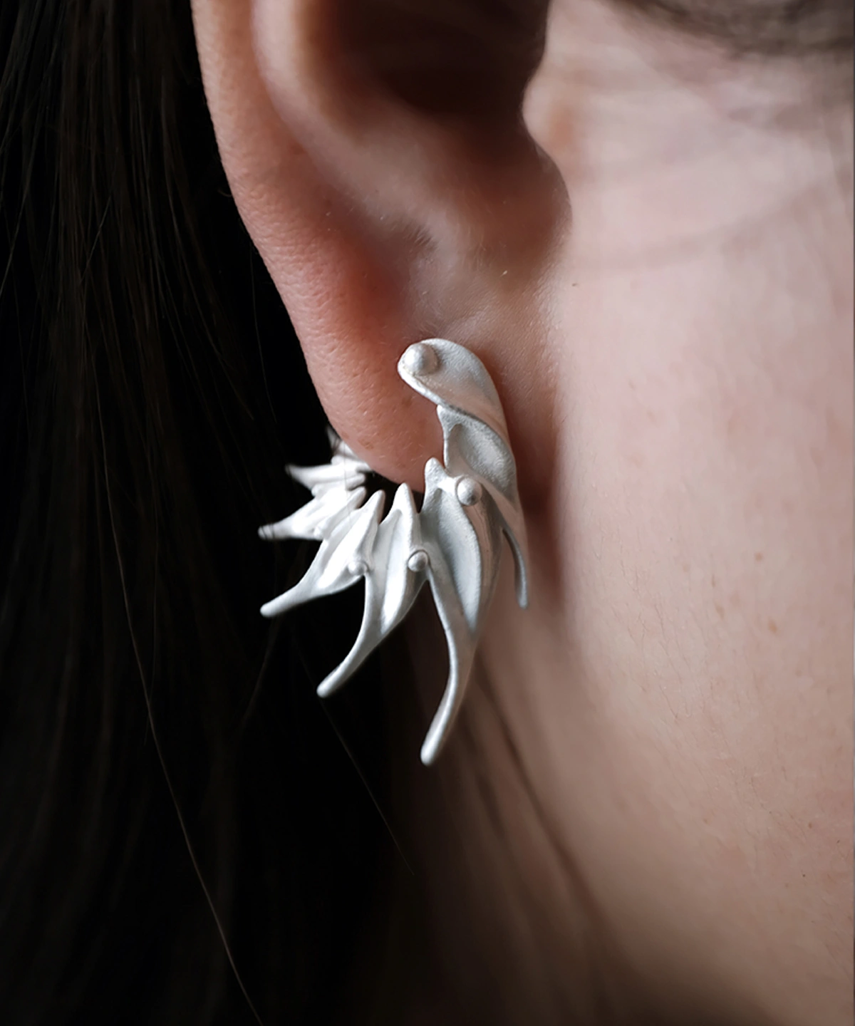 Close‑up of Lazesoul Ethereal Wings S925 Sterling Silver Designer Earrings worn on ear. Handmade art jewelry with flowing, wing‑inspired curves and sculptural organic design. Unique designer earrings showcasing elegance, craftsmanship, and modern style.