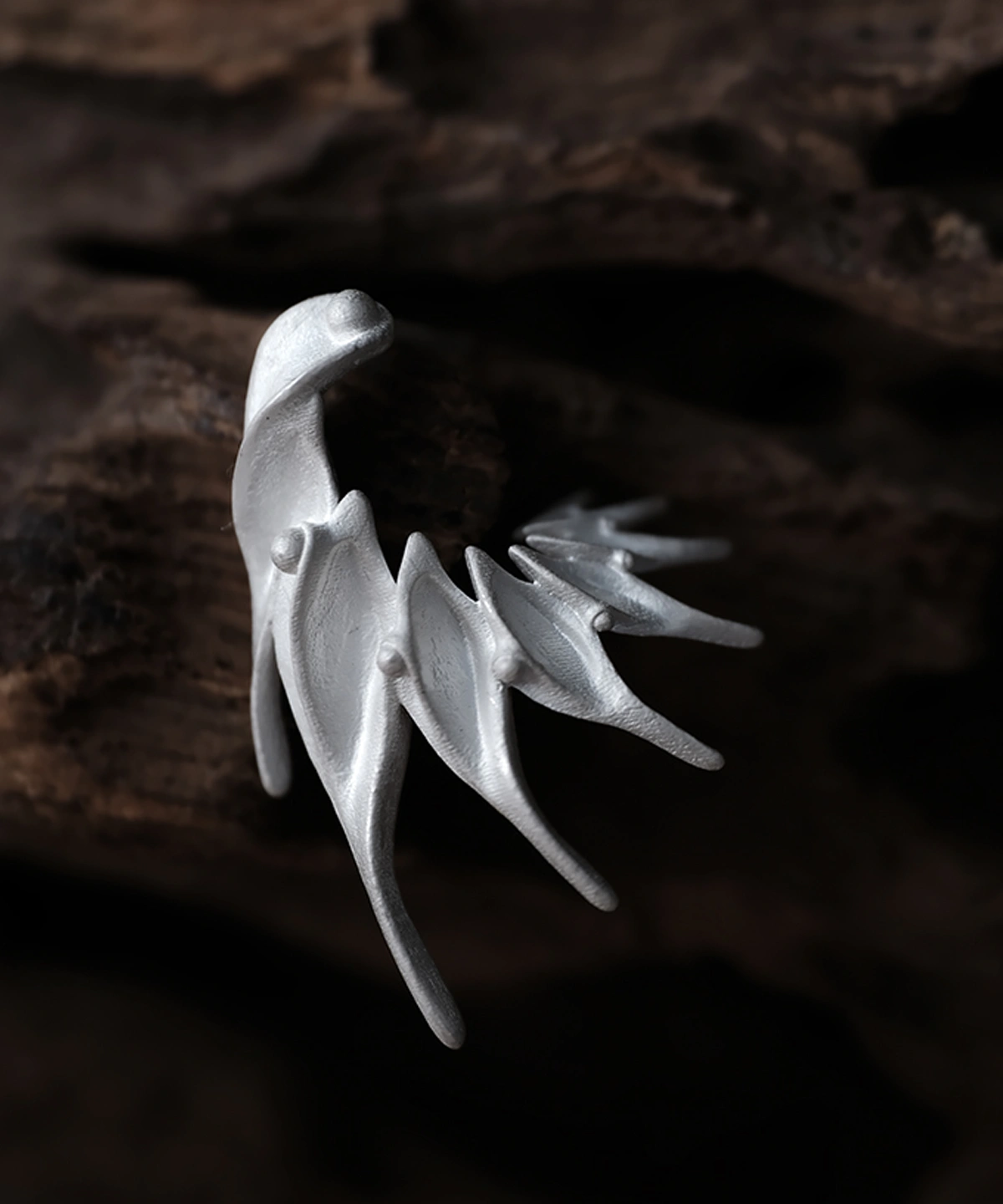Ethereal Wings designer earrings in S925 sterling silver, handmade by Lazesoul. Abstract, wing‑inspired sculptural forms with flowing lines and pointed tips, displayed on a dark wood background. Elegant artisan jewelry with fantasy and nature aesthetics.