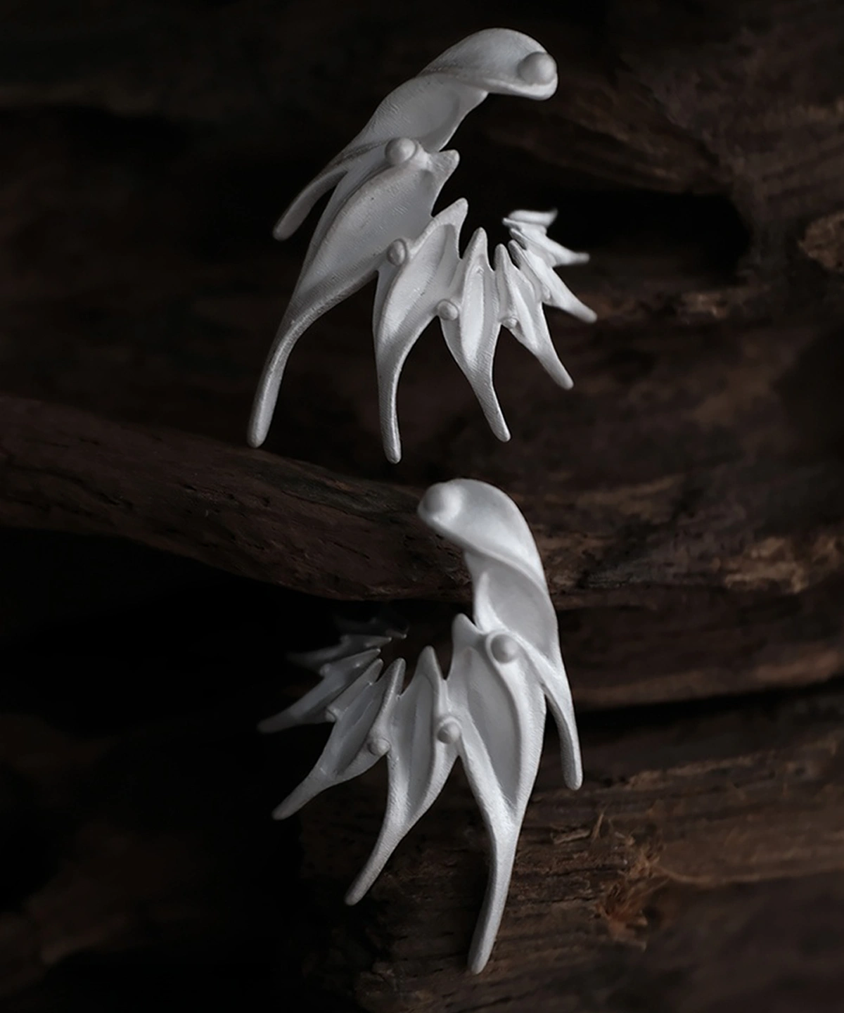 Ethereal Wings designer earrings in S925 sterling silver, handmade by Lazesoul. Sculptural, nature-inspired forms with flowing lines, set against a dark wood background. Elegant artisan jewelry with fantasy and organic aesthetics.