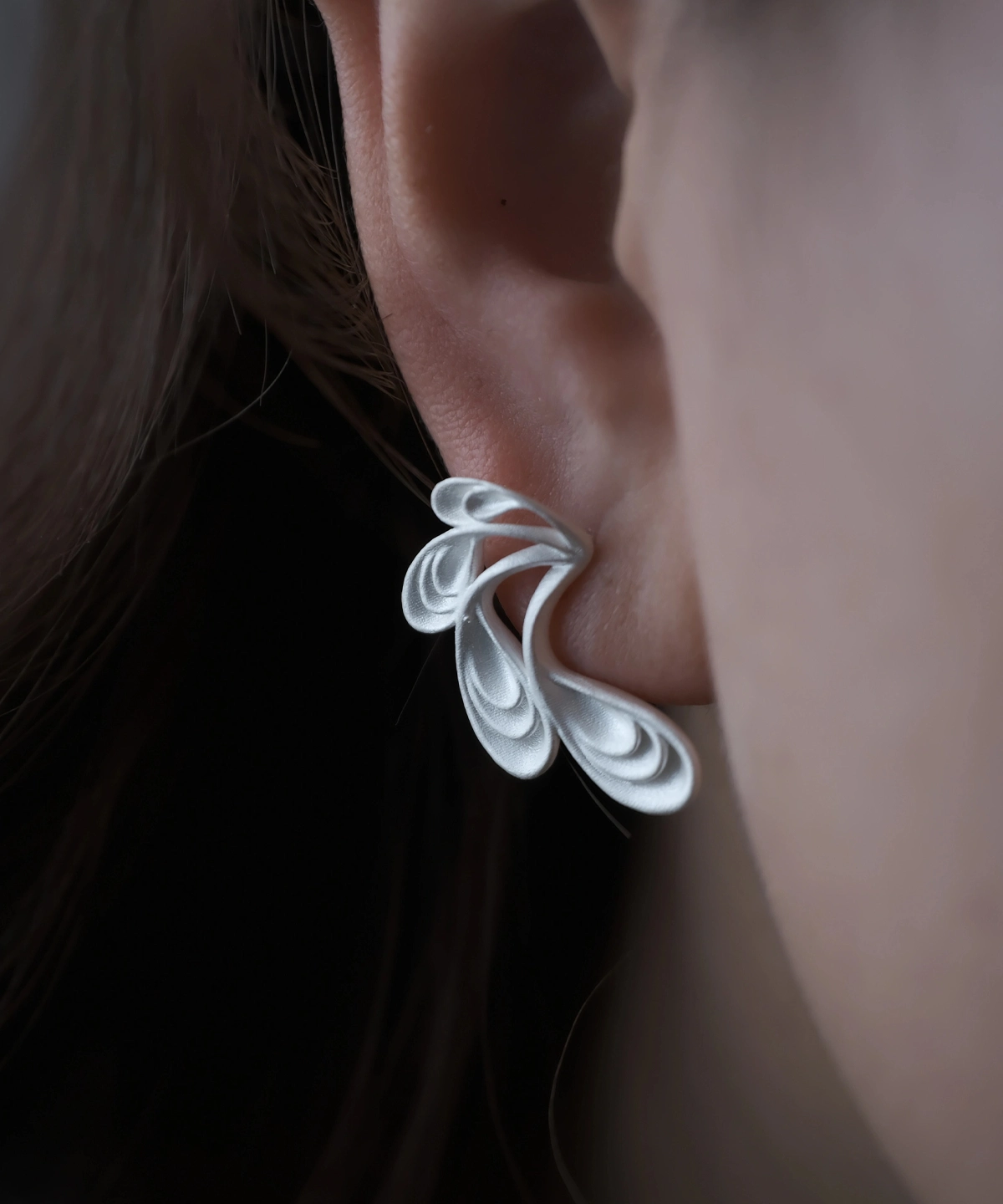Close‑up of Lazesoul Sylph Dancer S925 Sterling Silver Handmade Earrings worn on ear, featuring sculptural flowing petal design with fantasy‑inspired curves, artisan craftsmanship, and elegant matte silver finish.