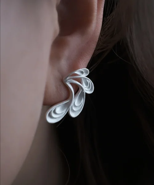 Close‑up of Lazesoul Sylph Dancer S925 Sterling Silver Handmade Earrings worn on ear, featuring sculptural flowing petal design with fantasy‑inspired elegance, artisan craftsmanship, and modern art jewelry style.