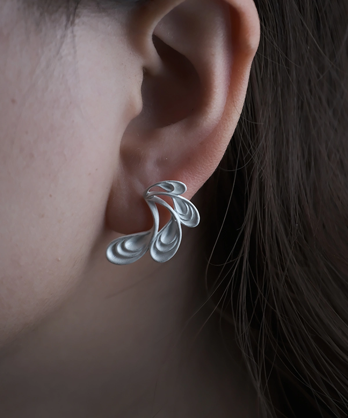 Sylph Dancer S925 Sterling Silver Fantasy Handmade Earrings by Lazesoul. Worn close‑up, the fluid petal‑like design shines against dark hair, showcasing artisan craftsmanship, organic elegance, and fantasy‑inspired artistry in Handmade Earrings.