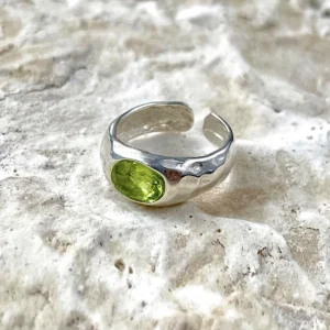 Sterling Silver Ring with oval-shaped natural peridot gemstone displayed on textured stone; elegant August Birthstone Ring design with open-ended band and handcrafted Silver Ring texture, showcasing vibrant green hues and artisanal detail.