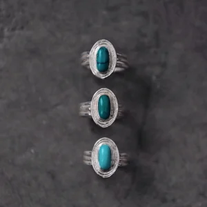 December Birthstone Ring-Natural Turquoise Ring in Sterling Silver 03 Three sterling silver December Birthstone Rings with natural turquoise stones arranged vertically on a dark textured surface, showcasing layered bands and unique turquoise hues.