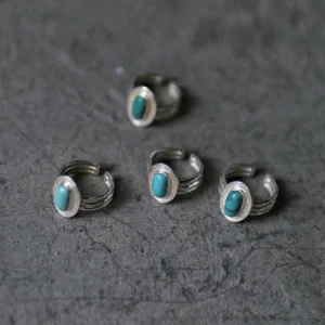 December Birthstone Ring-Natural Turquoise Ring in Sterling Silver 09 Four sterling silver December Birthstone Rings with natural turquoise stones arranged on a textured gray surface, showcasing split band designs and varying turquoise hues.