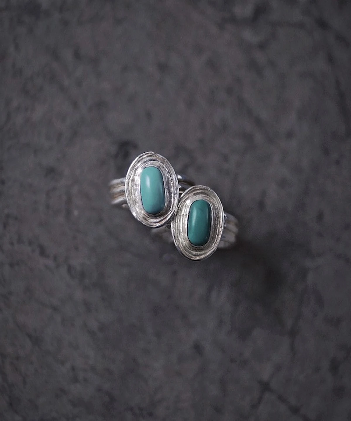 December Birthstone Ring-Natural Turquoise Ring in Sterling Silver 10 Two sterling silver December Birthstone Rings with natural turquoise stones placed on a dark textured surface, showcasing layered bezel settings and handcrafted detail.