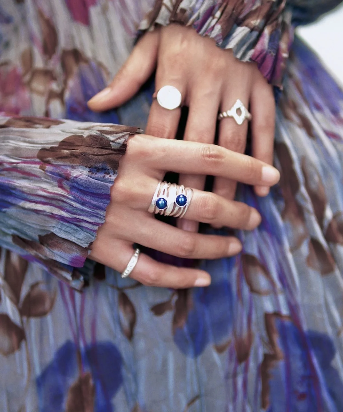 Two hands adorned with multiple Silver Rings, including June Birthstone Rings with natural black pearls; elegant Black Pearl Ring designs paired with floral-patterned sleeves, showcasing layered sterling silver craftsmanship and poetic styling.
