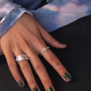 Hand with green nails wearing two sterling silver rings, including a November Birthstone Ring with topaz and beaded band, styled with heart tattoo and blue gemstone bracelet.