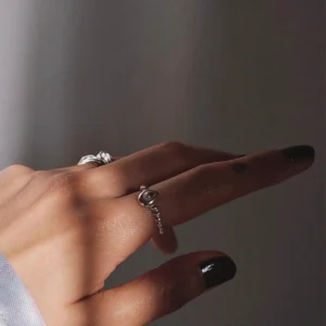 Hand with dark nails wearing sterling silver rings, including a twisted band November Birthstone Ring with topaz, styled in soft lighting to highlight texture and elegance.