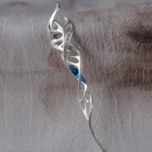 Close-up photo of Lazesoul Handmade S925 Sterling Silver Spiral Pendant Necklace on fabric background. The jewelry features flowing silver curves shaped like a spiral with leaf-like cutouts, centered by a vivid blue zircon gemstone. Elegant spiral pendant design.