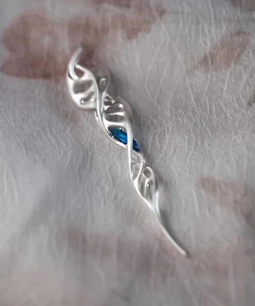 Close-up of Lazesoul Handmade S925 Sterling Silver Spiral Pendant Necklace on fabric background. The spiral pendant features a double helix design in polished silver with a vivid blue gemstone at the center, highlighting the elegant spiral necklace craftsmanship.