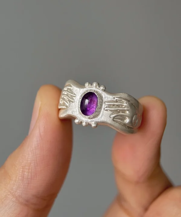 Handcrafted 999 Silver Ring featuring a vibrant purple Natural Amethyst gemstone with intricate engraved details and bead accents; a celestial-inspired Natural Amethyst Ring held in hand, showcasing artisanal texture and cosmic charm.