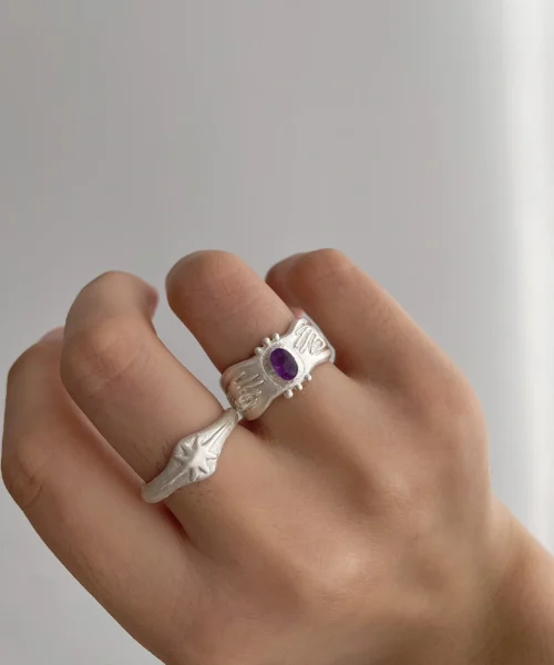 999 Silver Ring with oval Natural Amethyst gemstone and engraved cosmic patterns, worn on middle and ring fingers; a handcrafted Natural Amethyst Ring paired with star-motif silver band, styled in soft lighting.