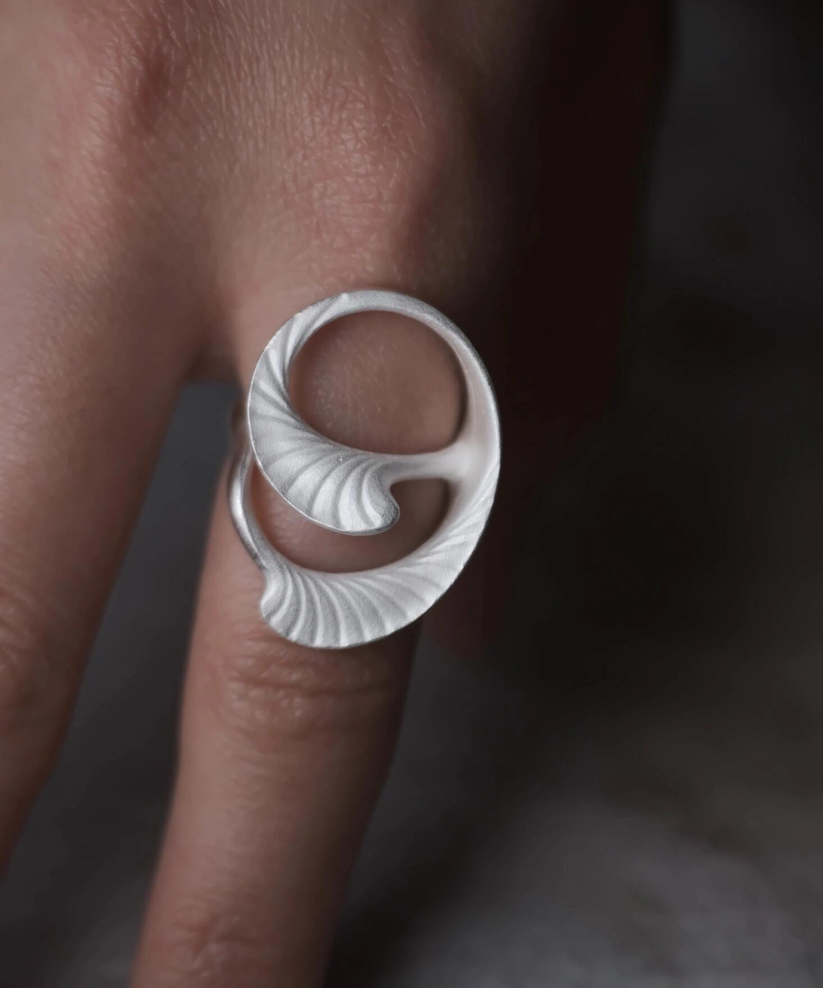Arc Glow S925 Sterling Silver Ring with sculptural curled leaf-inspired design and fine ridged texture; a nature-inspired Unique Ring featuring smooth flowing form, worn on hand and styled against a dark background.