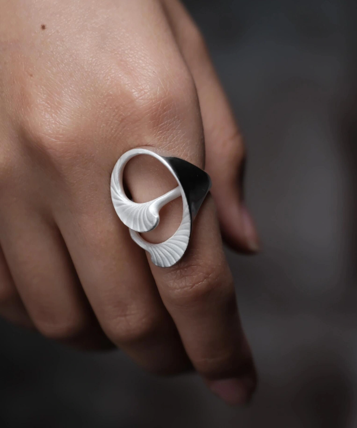 Arc Glow S925 Sterling Silver Ring with sculptural two-tone design, featuring glossy black and matte white curved forms; a nature-inspired Unique Ring with fine ridged textures, worn on hand and styled in close-up view.