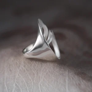 Arc Glow S925 Sterling Silver Ring with sculptural flowing design, featuring polished curves and organic form; a nature-inspired Unique Ring worn on hand, styled against soft neutral fabric for elegant contrast.