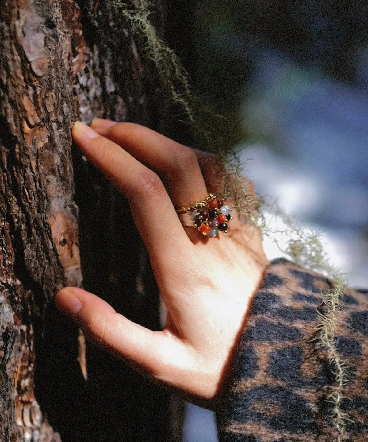925 Sterling Silver Ring with multicolored Natural Stone beads and golden leaf accents, worn on hand touching tree bark with moss and lichen; a handcrafted Silver Ring blending organic charm and forest-inspired elegance.