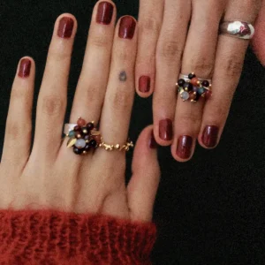 925 Sterling Silver Ring with multicolored Natural Stone beads in black, red, purple, and gold, worn on manicured hands with burgundy nails and paired with gold and silver bands; a handcrafted Silver Ring showcasing vibrant detail and artistic style.