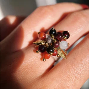 925 Sterling Silver Ring with multicolored Natural Stone beads in red, black, orange, and translucent white, accented with golden leaves and spheres; a handcrafted Silver Ring worn on hand in close-up view.