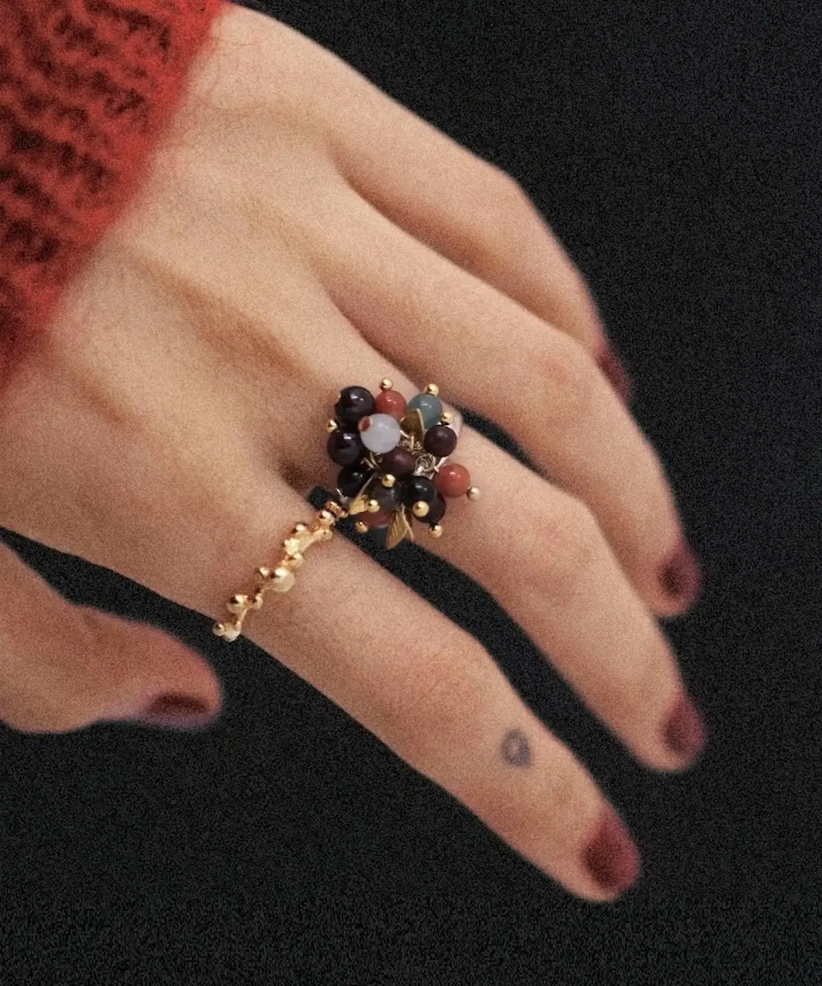 925 Sterling Silver Ring with multicolored Natural Stone beads in red, black, blue, and white, accented with golden leaves and spheres; a handcrafted Silver Ring worn on hand with dark red nails and heart tattoo, styled against dark background.